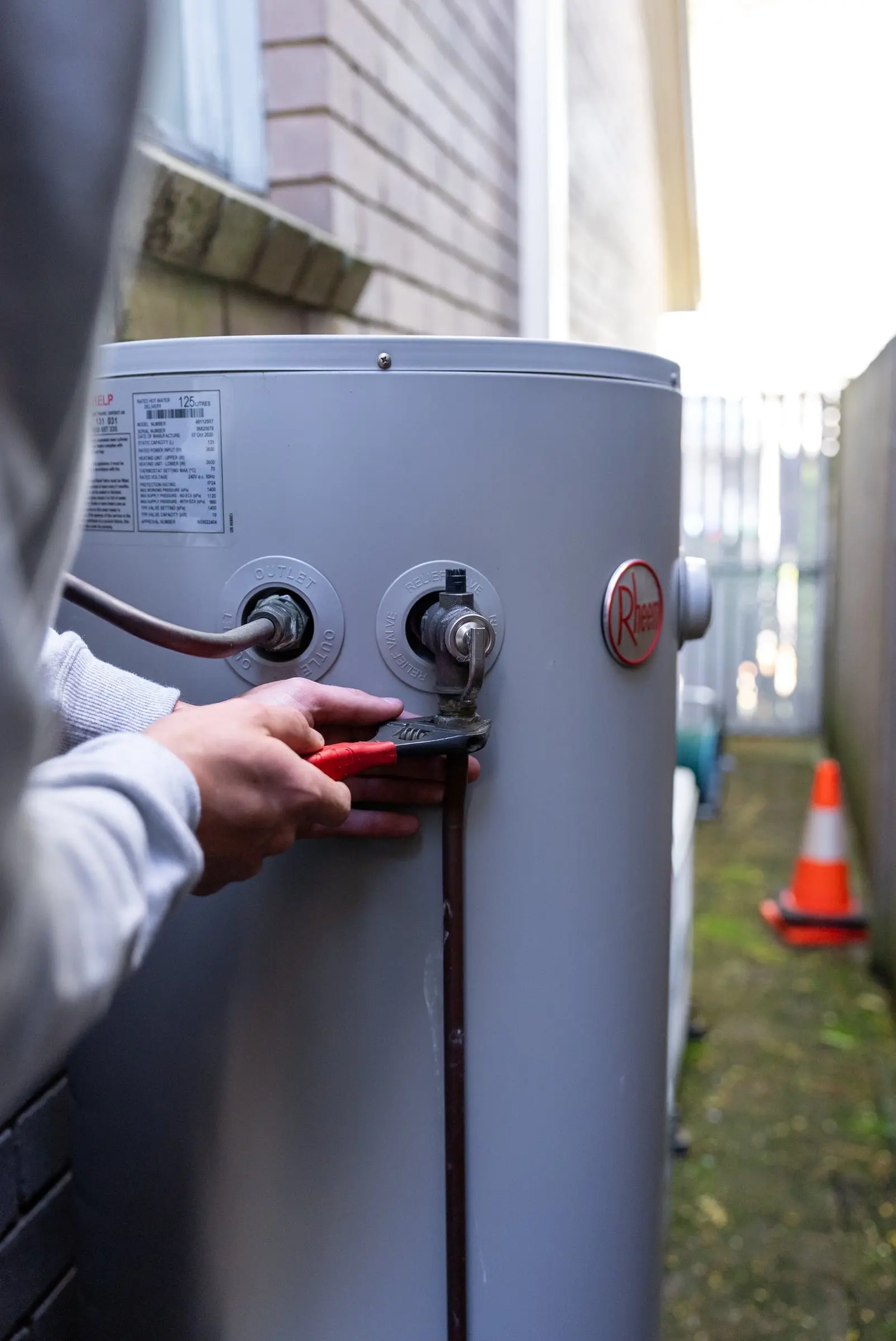 Plumber's hands adjusting a valve on a hot water system