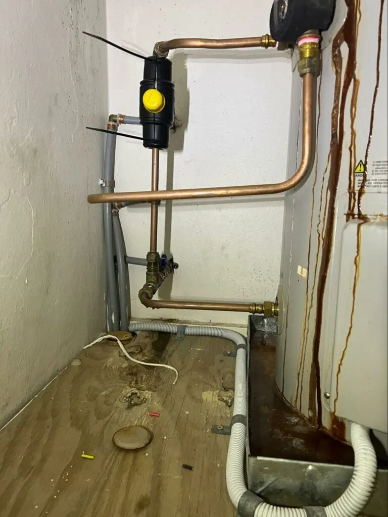 Rust-stained leak running down a hot water unit in a cupboard