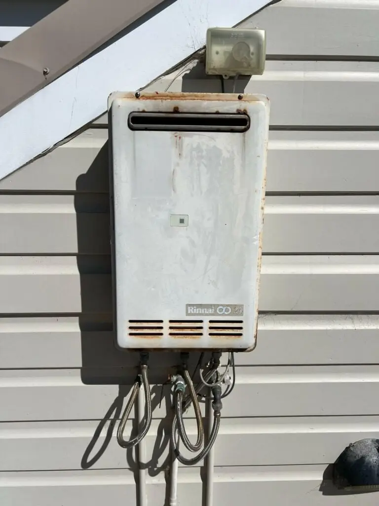 Old continuous flow hot water unit mounted on an outside wall