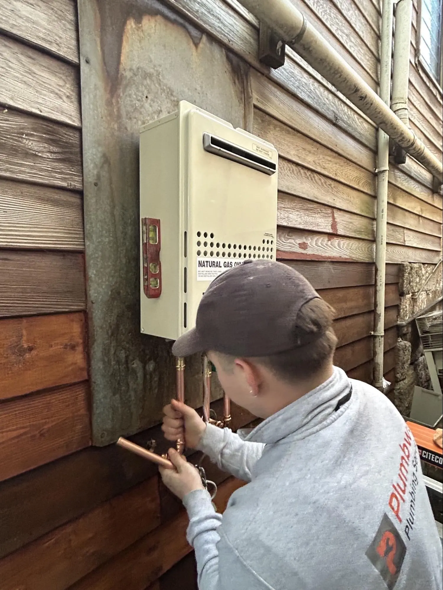 Plumber connecting copper pipes to a continuous flow hot water unit