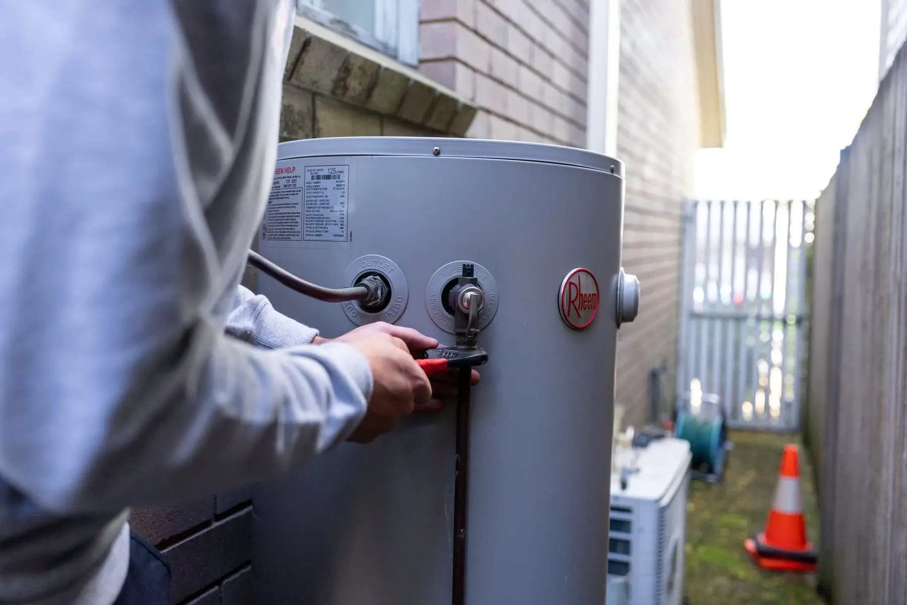 Plumber working on the valves of an electric hot water cylinder